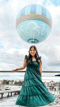 a woman in a green dress holding onto a blue hot air balloon