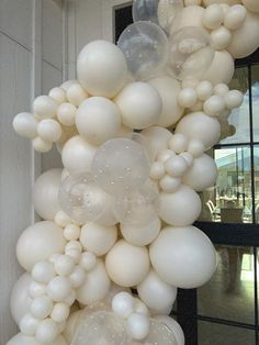 a bunch of white balloons hanging from the side of a building