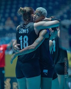 two female volleyball players hugging each other on the court