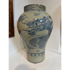 a blue and white vase sitting on top of a table next to a framed painting