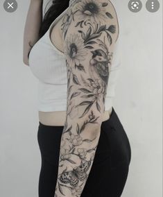 a woman's arm with flowers and birds tattooed on the back of her arm