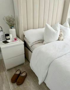 a bed with white sheets and pillows on top of it next to a night stand