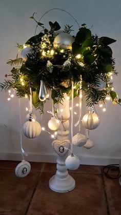 a white vase filled with christmas ornaments and greenery on top of a wooden table