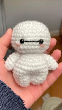 a hand holding a small white crocheted stuffed animal