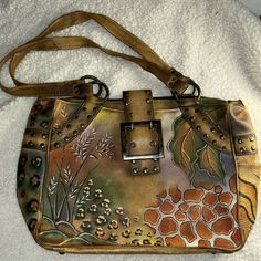 Medium Sized Hand Painted Studded Tote Bag With Large Buckle Clasp By Anuschka. Good Condition But Shows Some Signs Of Wear. One Side Pocket And Zipper Pocket On The Back. Pockets On Inside As Well With Two Separate Zippered Sides. Artisan Hand Painted Brown Bags, Anuschka Handbags Unique, Hand Painted Brown Rectangular Shoulder Bag, Artistic Hand Painted Satchel Shoulder Bag, Everyday Rectangular Hand-painted Shoulder Bag, Painted Tote Bag, Painted Tote, Side Pocket, Womens Tote Bags