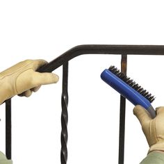 a person holding a brush on top of a metal hand rail next to a pair of gloves