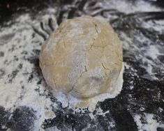 a ball of dough sitting on top of a black tablecloth covered in white flour