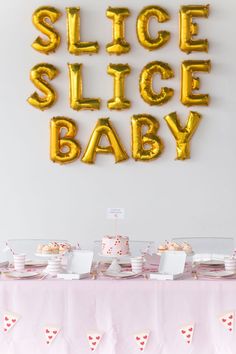 a table topped with lots of balloons and desserts next to a sign that says slice slice baby