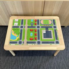 a toy table with cars and roads on it in front of some cupboards or drawers