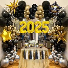 a table topped with balloons and black and gold decorations