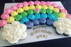 a birthday cake with cupcakes in the shape of a rainbow and flowers on it