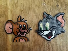 two pieces of perler bead art sitting on top of a wooden table next to each other