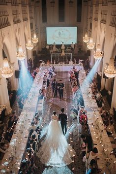 a bride and groom walking down the aisle at their wedding ceremony in an ornate ballroom