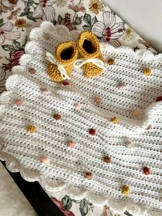 a crocheted baby blanket with yellow shoes on it