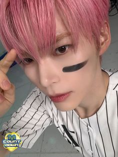 a young man with pink hair and black eyeliners on his face is posing for the camera