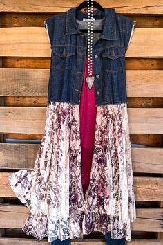 a denim jacket hanging up against a wooden wall with jeans on it and a pink dress underneath