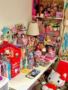 a room filled with lots of toys and dolls on top of a white desk next to a lamp