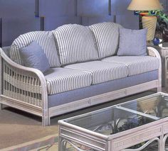 a white wicker couch sitting next to a glass table