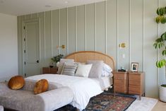 a large bed sitting in the middle of a bedroom next to a dresser and potted plant