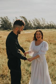 a man and woman standing next to each other in a field