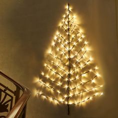 a lighted christmas tree next to a stair case