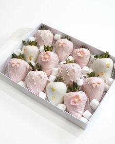 a box filled with lots of pink and white chocolate covered strawberries on top of marshmallows