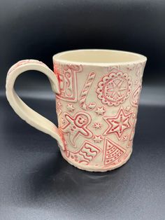 a red and white coffee cup sitting on top of a black table next to a gray wall