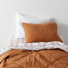 a bed with two pillows on top of it next to a pillow case and blanket