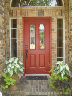 a red door with two planters in front of it and an arched glass window