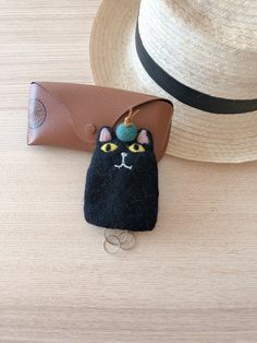 a black cat coin purse sitting on top of a wooden table next to a straw hat