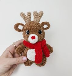 a hand holding a small brown and white crocheted stuffed animal with a red scarf around it's neck