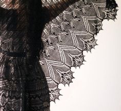 a woman wearing a black lace dress and holding her arms behind her back