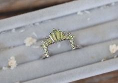 a diamond ring sitting on top of a piece of silver foil with flowers around it