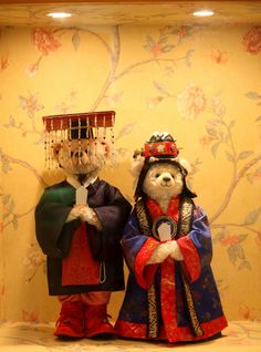 two teddy bears dressed in traditional chinese costumes and headgear standing next to each other