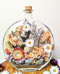 a vase filled with lots of flowers on top of a wooden table next to white and yellow daisies