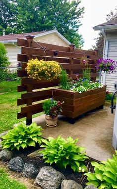 a wooden planter filled with lots of plants next to a house and trees in the back yard