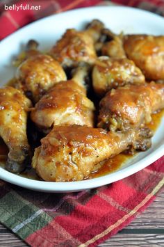 chicken wings with sauce in a white bowl on a red and green checkered table cloth