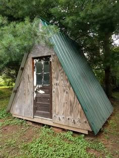 an outhouse with a metal roof and green tining on the top is shown in front of some trees