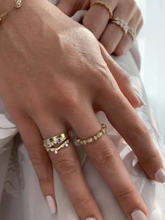 a woman's hand with three different rings on her left and the other hand wearing a white dress