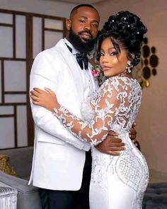 a man and woman dressed in white posing for a photo together, with one holding his arm around the other's shoulder