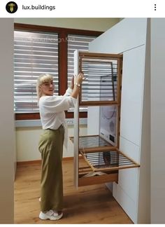 an older woman standing in front of a cabinet with the door open and drawers closed