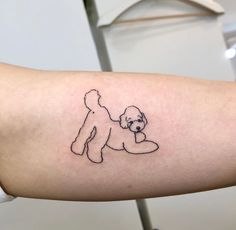 a small tattoo of a teddy bear on the right arm and shoulder, with an outline of a dog holding a toy in it's paws