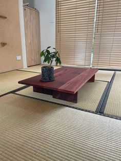 a wooden table sitting on top of a carpeted floor next to a potted plant