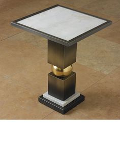 a small square table with two gold rings on it's sides and a white top