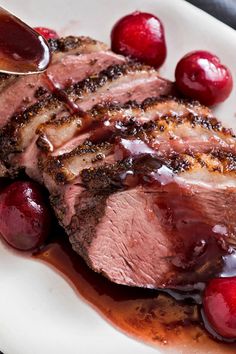 a white plate topped with meat and cherries