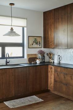 a kitchen with wooden cabinets and black counter tops, along with a rug on the floor