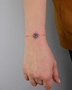 a woman's wrist with an eye tattoo on the left side of her arm