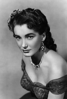 an old black and white photo of a woman in a dress with pearls on her head