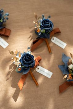 three boutonnieres with blue flowers and leaves on them sitting on a table