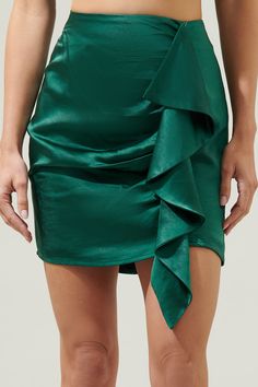 Add a little flirt factor to your 'fit and slip into the Drea Shirred Ruffle Mini Skirt. Silky, lightweight satin shapes this must-have closet staple that has a high-waisted silhouette and a front overlay that wraps together at the front and creates a ruffle effect. It has an invisible zipper in the back and it perfect to pair with the Drea Puff Sleeve Crop Top! - Ruffles- Shirred- Zipper back- Mini- Color: EmeraldSize + Fit - Model is 5'8" and wearing size XS- Measurements taken from size S - W Spring Satin Fitted Mini Skirt, Satin Pleated Skirt For Night Out, Party Satin Skirt With Folds, Chic Satin Tiered Skirt, Satin Ruffled Skirt For Party, Spring Satin Skirt With Ruffles, Fitted Silk Skirt For Date Night, Chic Satin Finish Bottoms For Party, Elegant Ruched Mini Skirt For Date Night